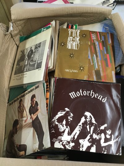 A box of 7" singles and EPs by various artists including Motörhead, The Jam, Klaxons, The Creatures and many more.