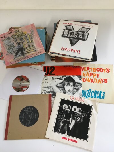 A collection of 7" singles by various artists including The Beatles, Buzzcocks, Queen and others.
