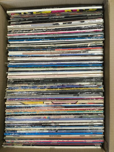 A box of LPs and 12" singles by various artists including Michael Jackson, Queen, The Charlatans, The Cure and many more.