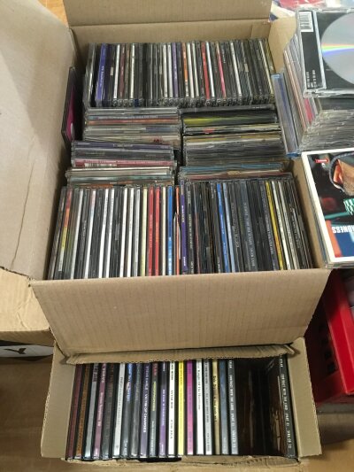 Three boxes of rock and pop CD singles and albums.