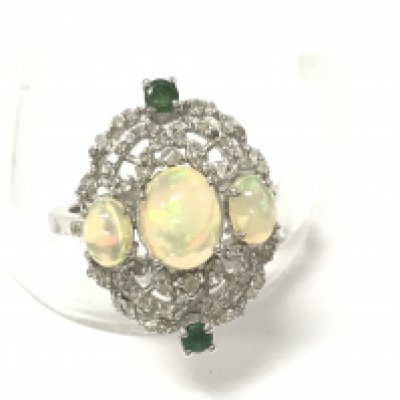 An ornate silver ring set with 3 oval cabochon opals 2 emeralds and several diamonds. Opals approx 2ct emeralds 0.20ct and diamonds 0.18ct. Size P 1/2