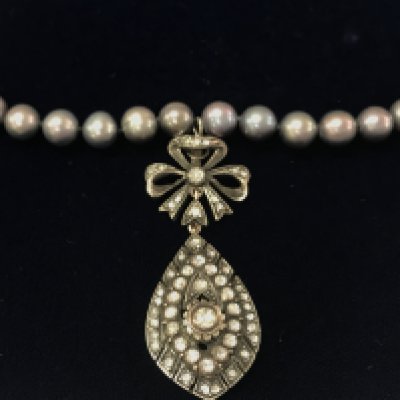 An unusual necklace strung with grey cultured Pearl with a white metal flamingo clasp and a silver and low carat gold hand made vintage style bow and pear shaped pendant set with rose cut diamonds approx 1ct. Postage B