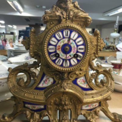 A french gilt clock the blue floral dial with Roman numerals above a flying eagle.
