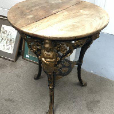 A Victorian cast iron pub table with lion paw feet, lion head, floral decoration and figures.