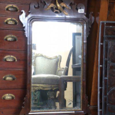 A Georgian mahogany wall mirror, the carved pediment in the form of a stylised bird. 45cm x 95cm