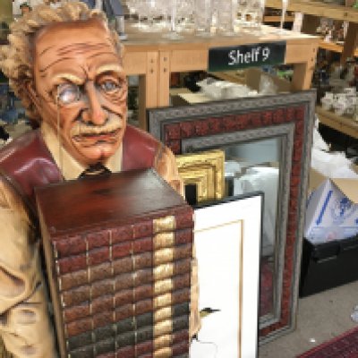 Fiberglass sculpture of Albert Einstein holding a stack of books which is actually a wooden cabinet 53 inches tall.