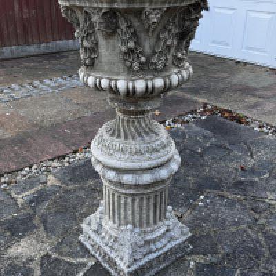 A large cast concrete planter with grape vine design.
