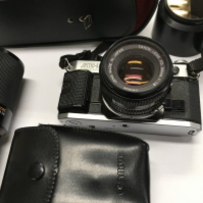 A canon AE-1 camera with additional lenses and a flash with other accessories.