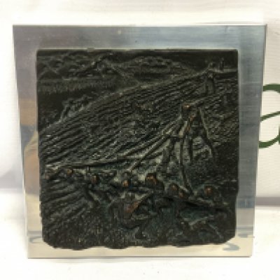 A small Bronze plaque depicting a farming scene, mounted 12.5cm x 12.5cm.