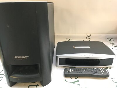 A Bose Surround system module and remote control plus one Bose Acoustimass powered subwoofer speaker.