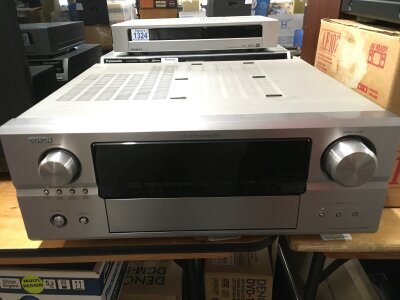A boxed Denon AVR 2807 surround receiver with remote control, manual and power lead and a boxed surround sound set of eight Q Acoustics speakers in a high gloss black finish.