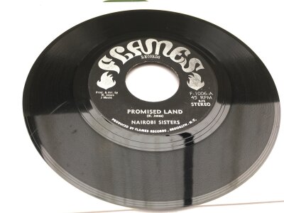 A rare original USA roots reggae 7" single of Promised Land b/w (dub version) by Nairobi Sisters, 1970s release on Flame Records F-1006. Vinyl VG+/EX.