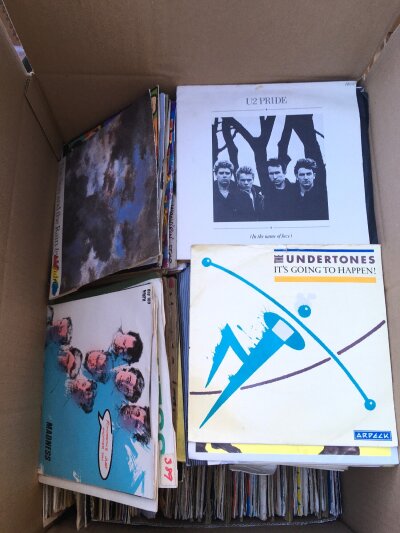 A box of 7" singles by various artists including The Undertones, X Ray Spex, Bob Marley and many more.