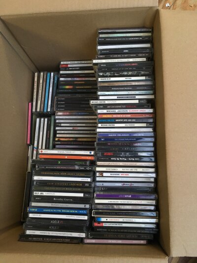 A box of CDs by various artists including David Bowie, Genesis, London Grammar and many more.