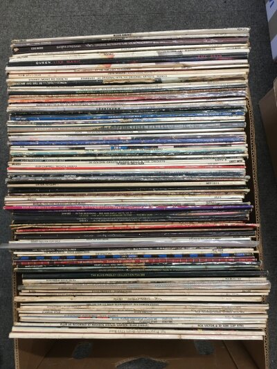 A box of LPs and 12" singles by various artists including The Beatles, Elvis Presley, Queen and others.