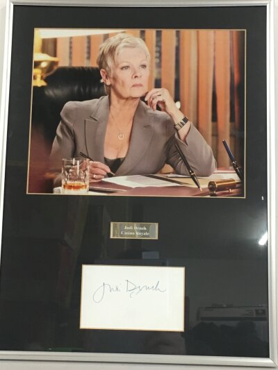 A framed and signed display of Judi Dench as M from the James Bond franchise, approx 32cm x 42cm including frame.