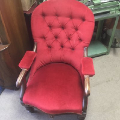 A Victorian open armchair with red upholstery.
