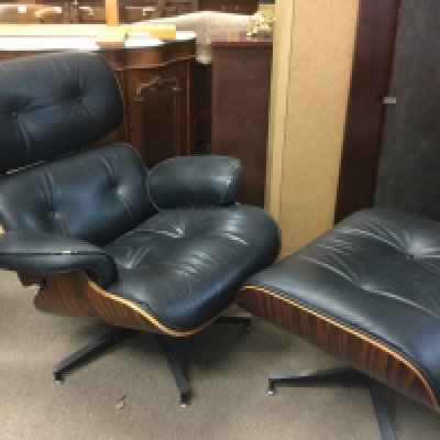 An Eames style black leather chair and footstool (2). Shipping category D.
