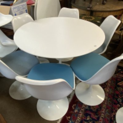 Mid Century Tulip dining suite (Table and 6 chairs) designed by Eero Saarinen 1956 (Finnish-American, 1910-1961) for Knoll, laminated top over a curved painted metal base, stamped 'Knoll Studio', 107cm diameter 73cm high, and six 'Tulip' chairs, each with a white plastic shell over a painted metal base. (Mixed Light blue / turquoise blue upholstered cushions).