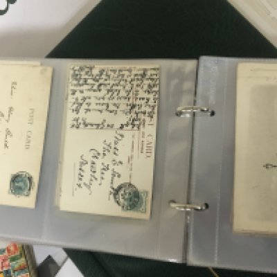 An album containing a good collection of Victorian postcards two Stamp collectors stock books and an album containing Elizabeth II stamps used and unused including pre-decimal stamps.